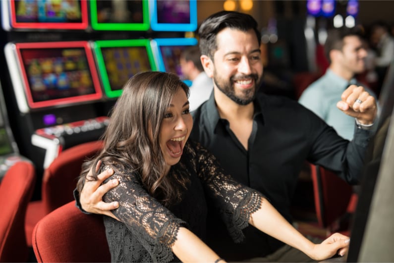 Good looking young couple celebrating and looking excited about hitting the jackpot in a slot machine