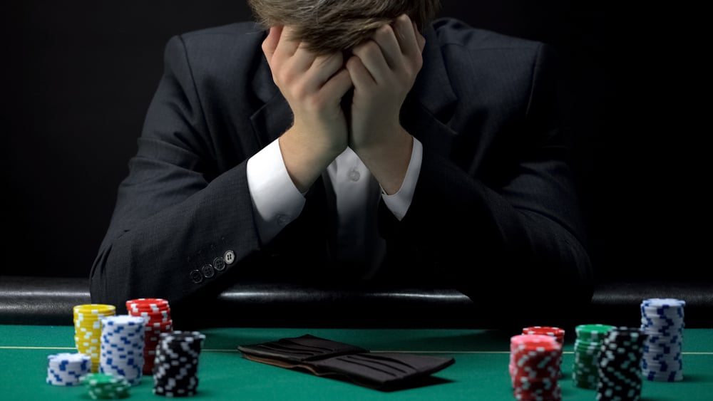 poker player holding head in hands after losing game