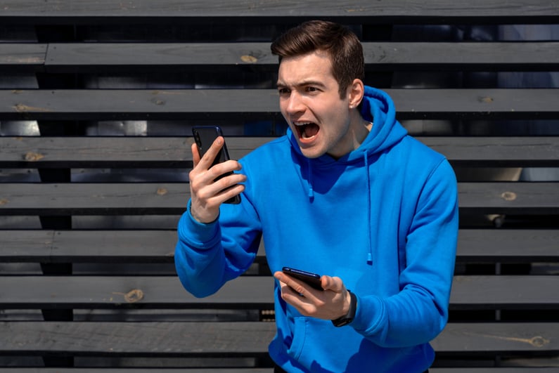 Man yelling into a phone while holding a second phone