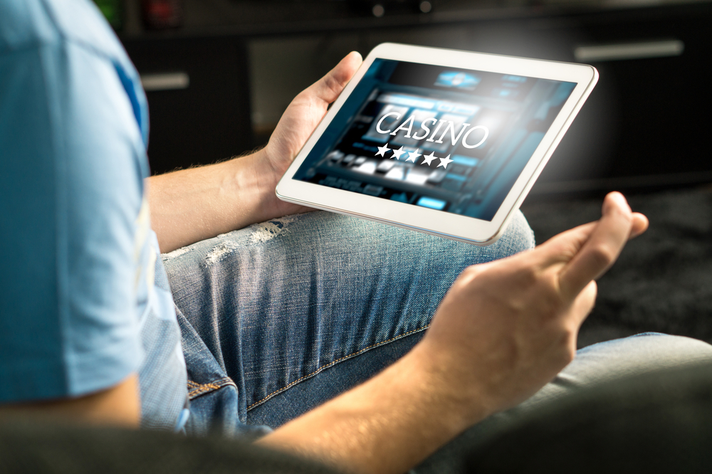 male crosses fingers as he gambles online on a tablet