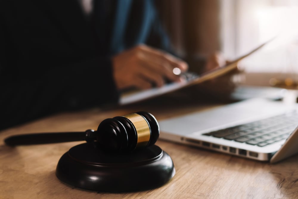 legal professional works at a desk with judge's gavel and laptop