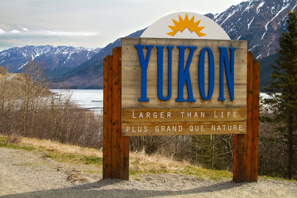 Signpost for the Yukon territory in Canada with lakes and mountains in the background