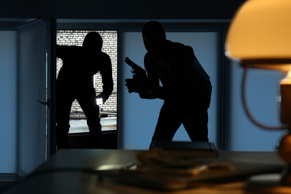 two armed burglars entering a dimly lit home