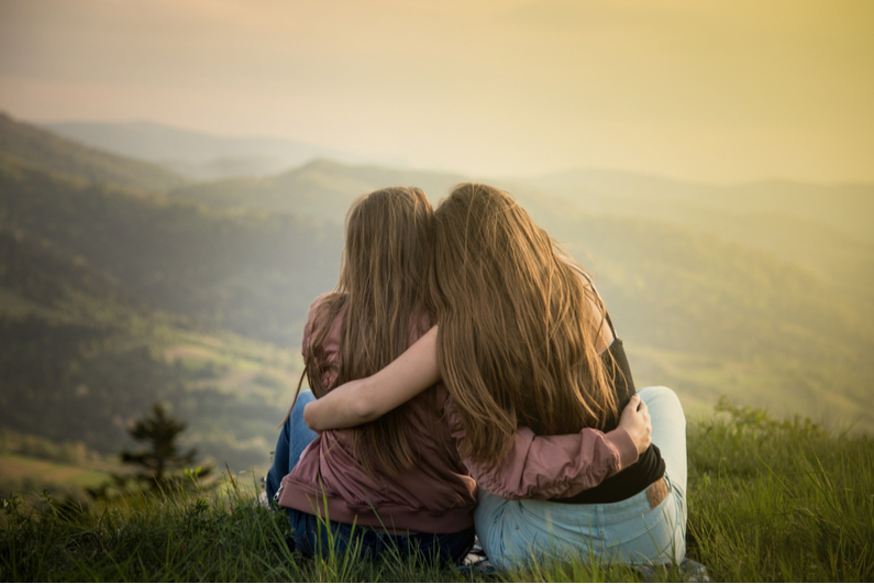 Two women watching a sunset in the mountains